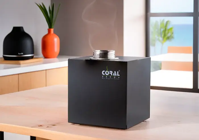 a black 360 diffuser of coral aroma, in front of a kitchen on a clean wooden table